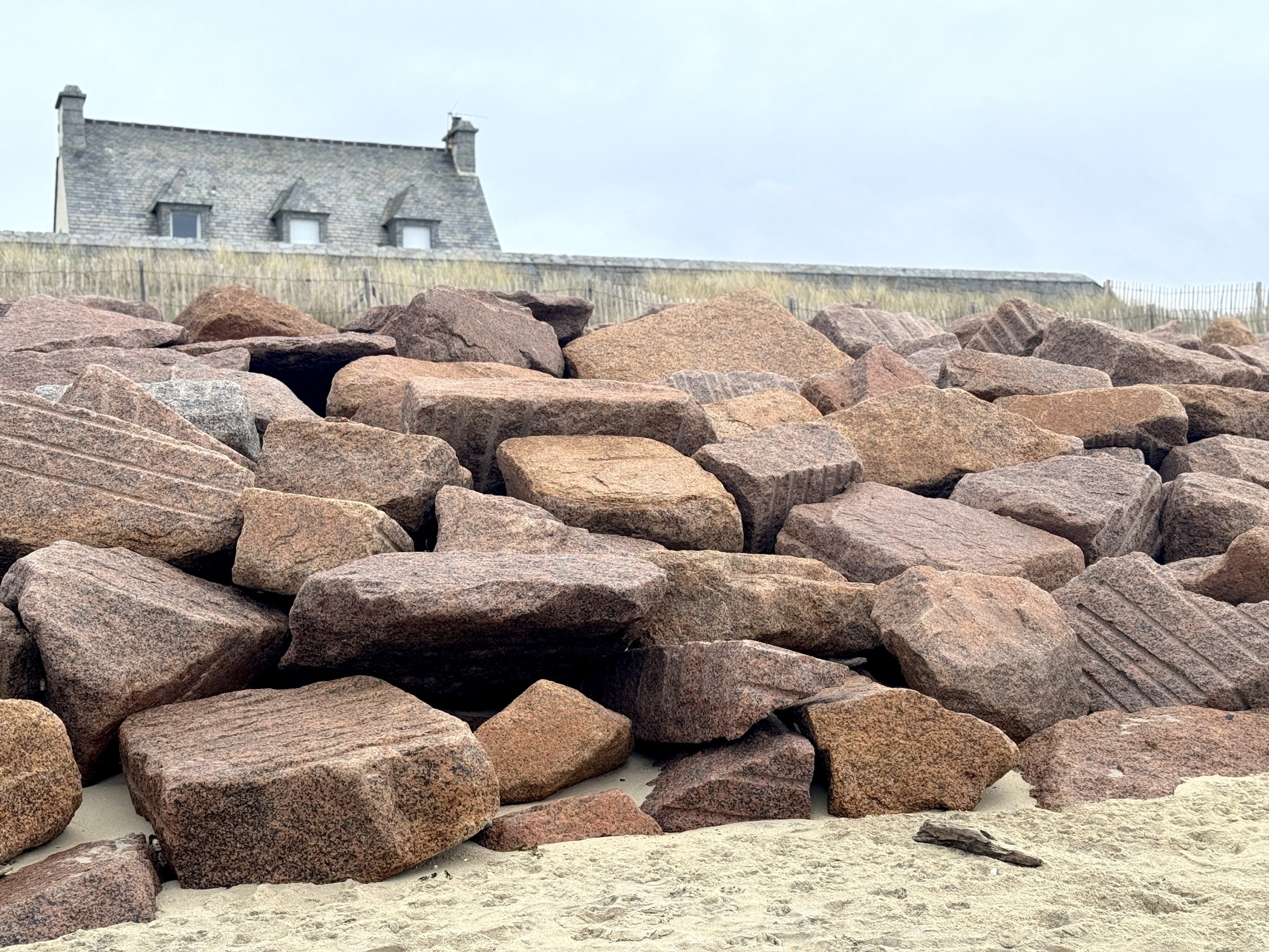 Peekaboohousefullroofpinkboulderssandgrayskyhorizontal